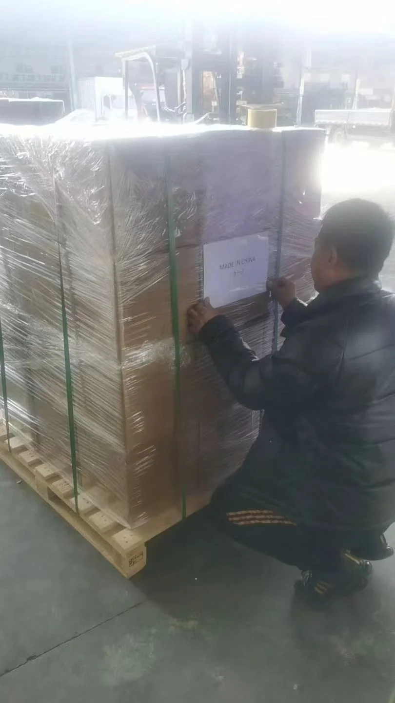 A worker attaching a label to a wrapped pallet of cartons