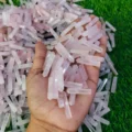 May include: A large pile of pink rose quartz points, some of which are being held in a hand. The points are various sizes and shapes.