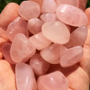 May include: A collection of tumbled rose quartz stones in various sizes and shapes. The stones are a pale pink color and have a smooth, polished finish.